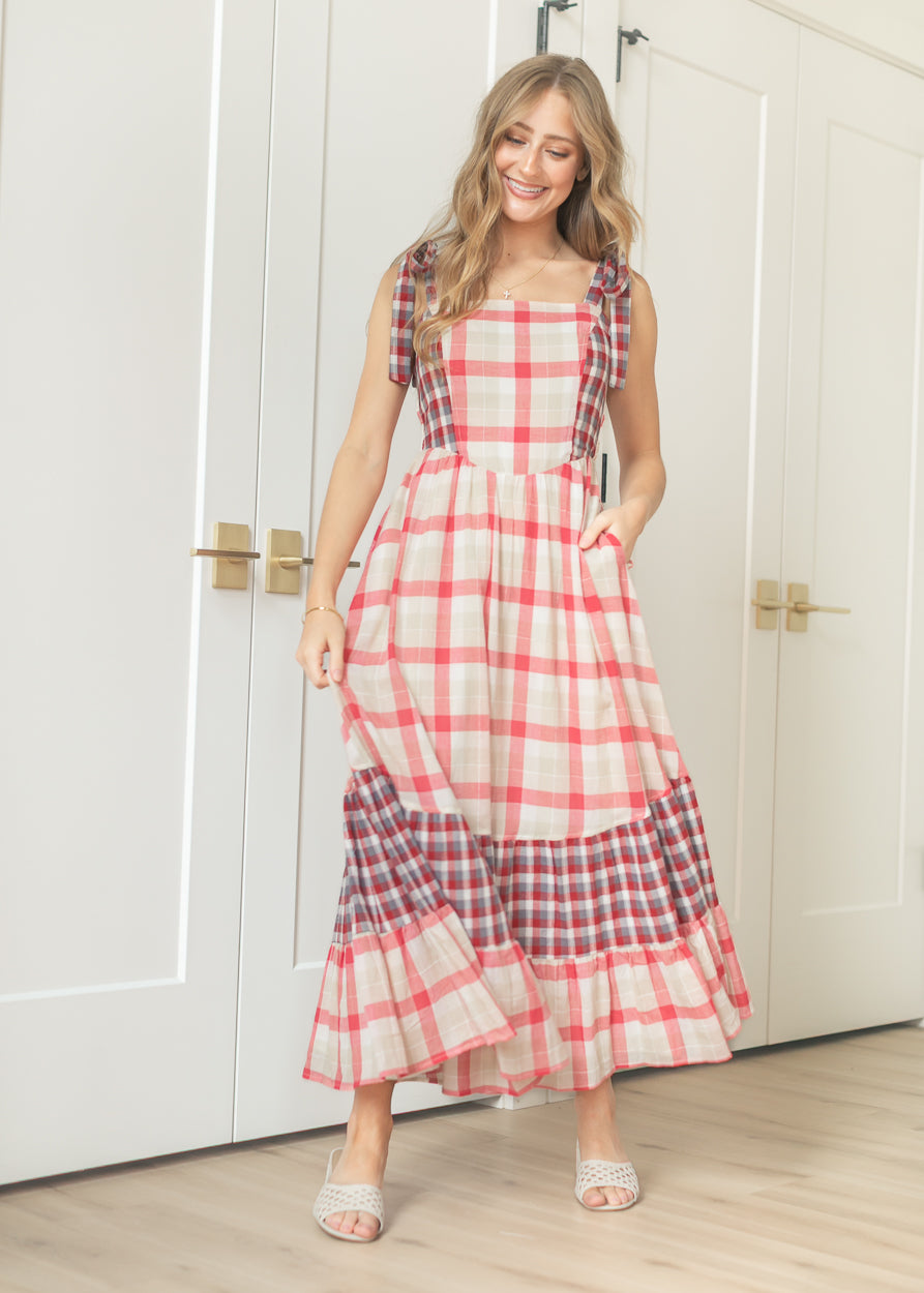 Cream and red plaid tie-shoulder maxi dress with square neckline and tiered contrast hem, styled with woven sandals