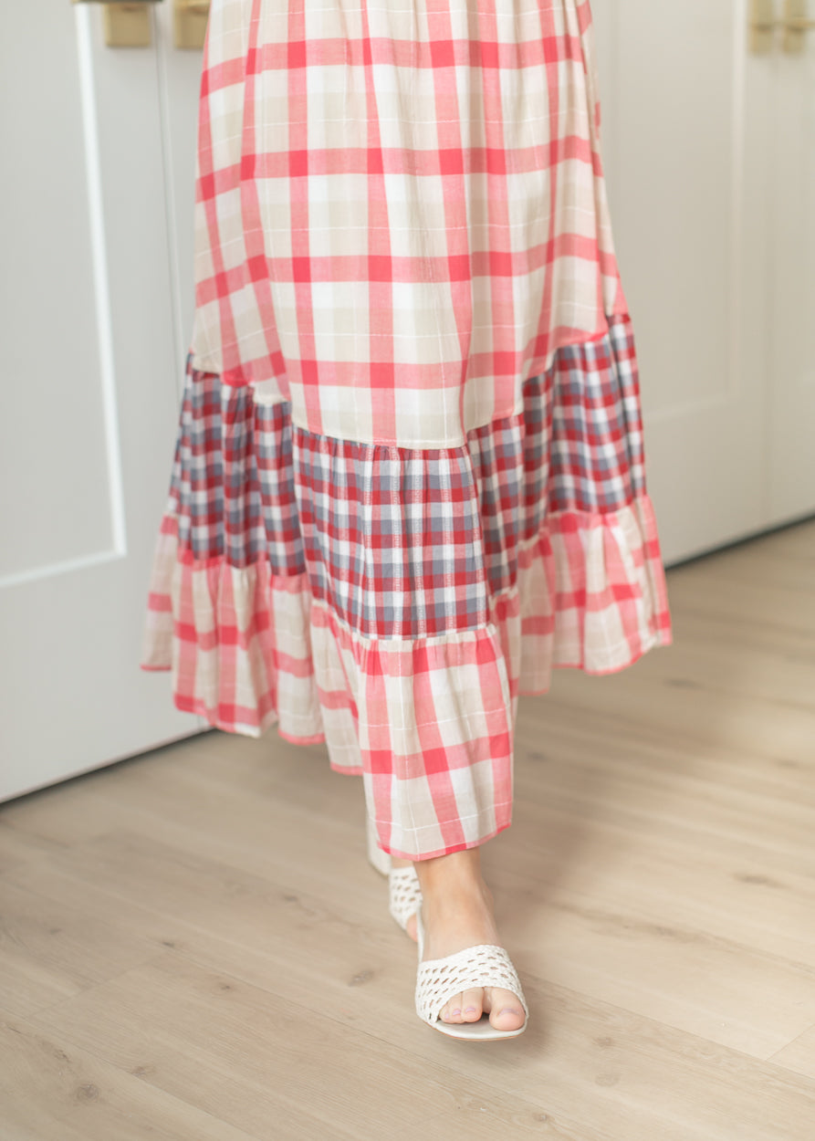Close-up of tiered maxi skirt hem with contrast plaid panel and woven slide sandals