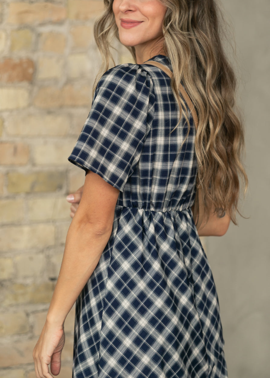 Close-up of navy plaid V-neck dress showing the tie neckline and softly gathered shoulder.