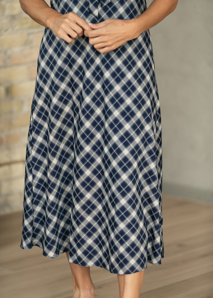 Close-up of navy plaid midi skirt showing the diagonal plaid pattern and flowing hem.