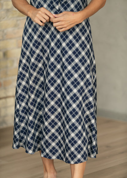 Close-up of navy plaid midi skirt showing the diagonal plaid pattern and flowing hem.