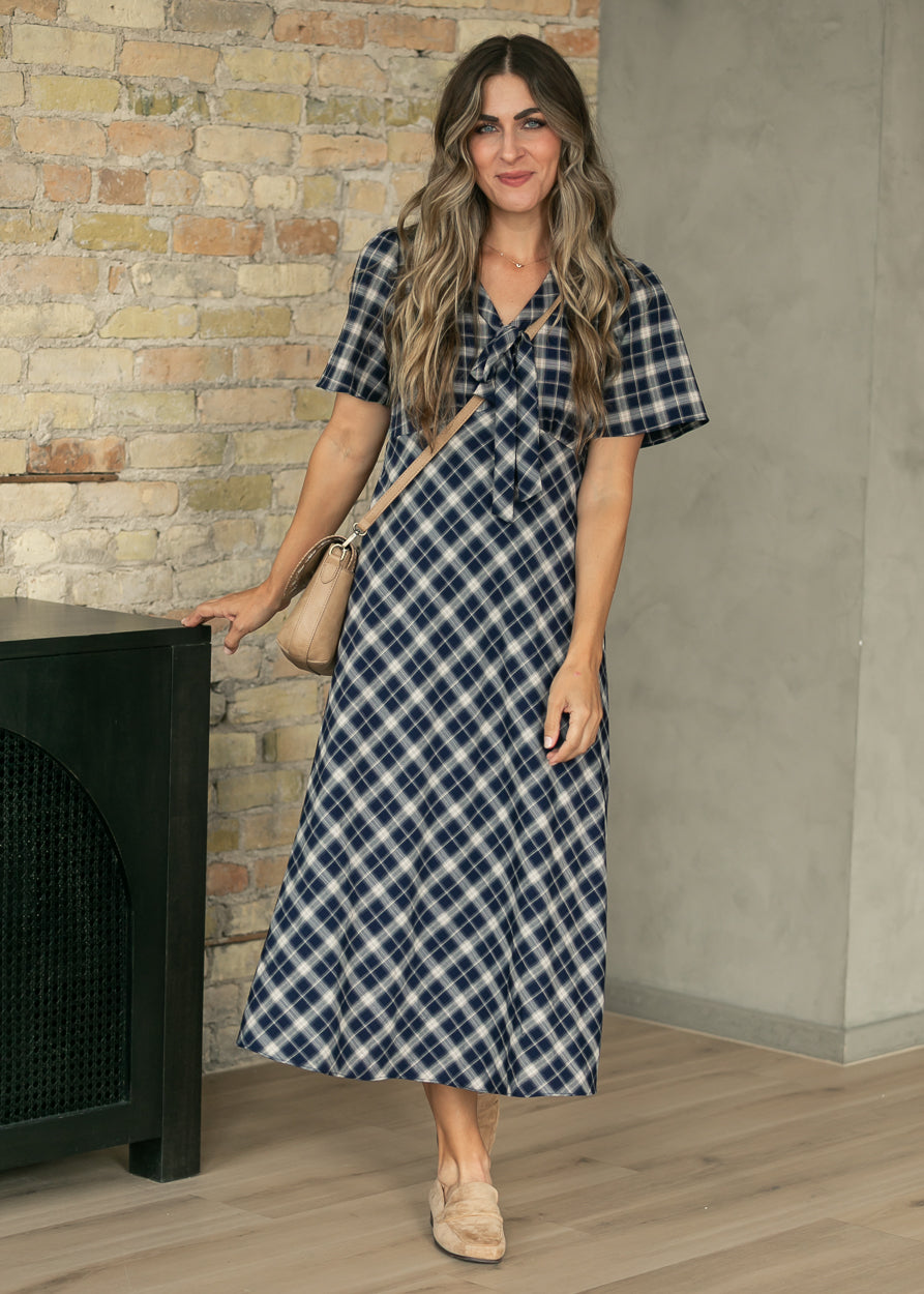 Navy plaid midi dress with short sleeves and flowing skirt, shown from a back three-quarter angle.