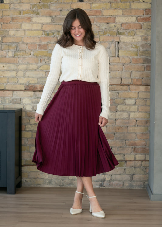 Burgundy pleated midi skirt showing movement and flow as the model walks forward.