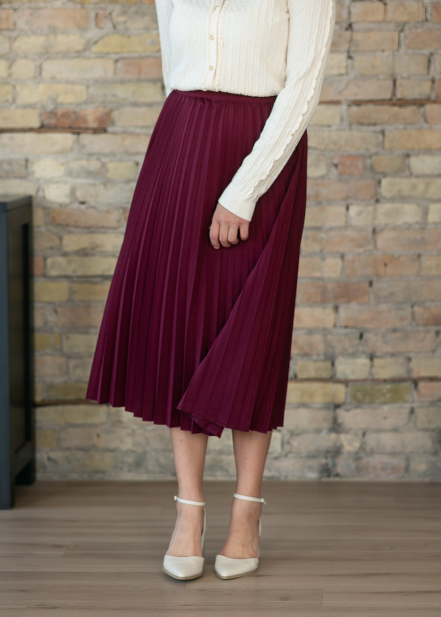 Burgundy pleated midi skirt showing stretchy elastic waistband detail.