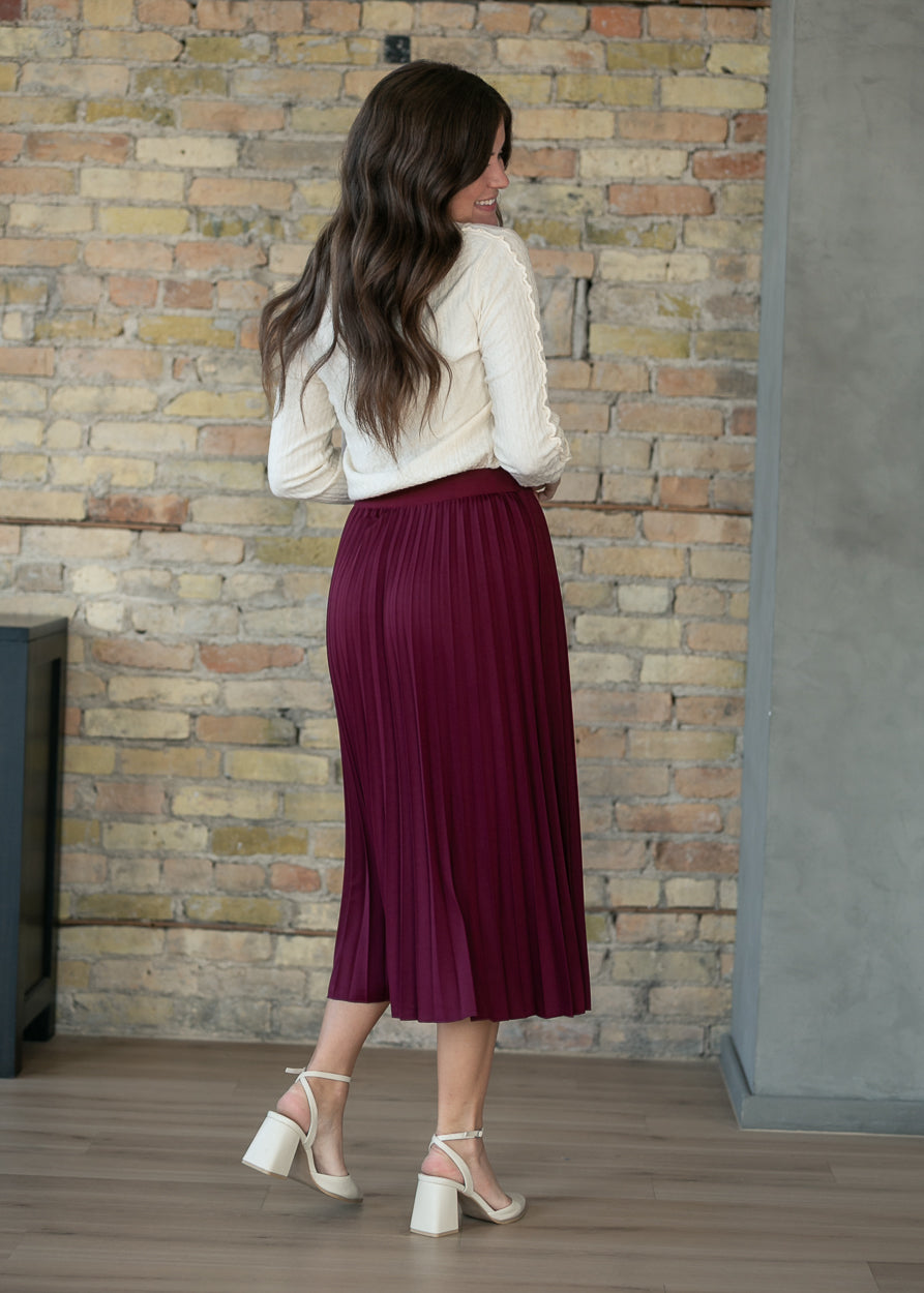 Back of burgundy pleated midi skirt, full-length view on 5'7" model, mid-calf hem.