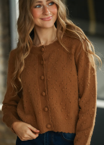 Camel pointelle knit cardigan showing the round neckline, button front and textured knit pattern.