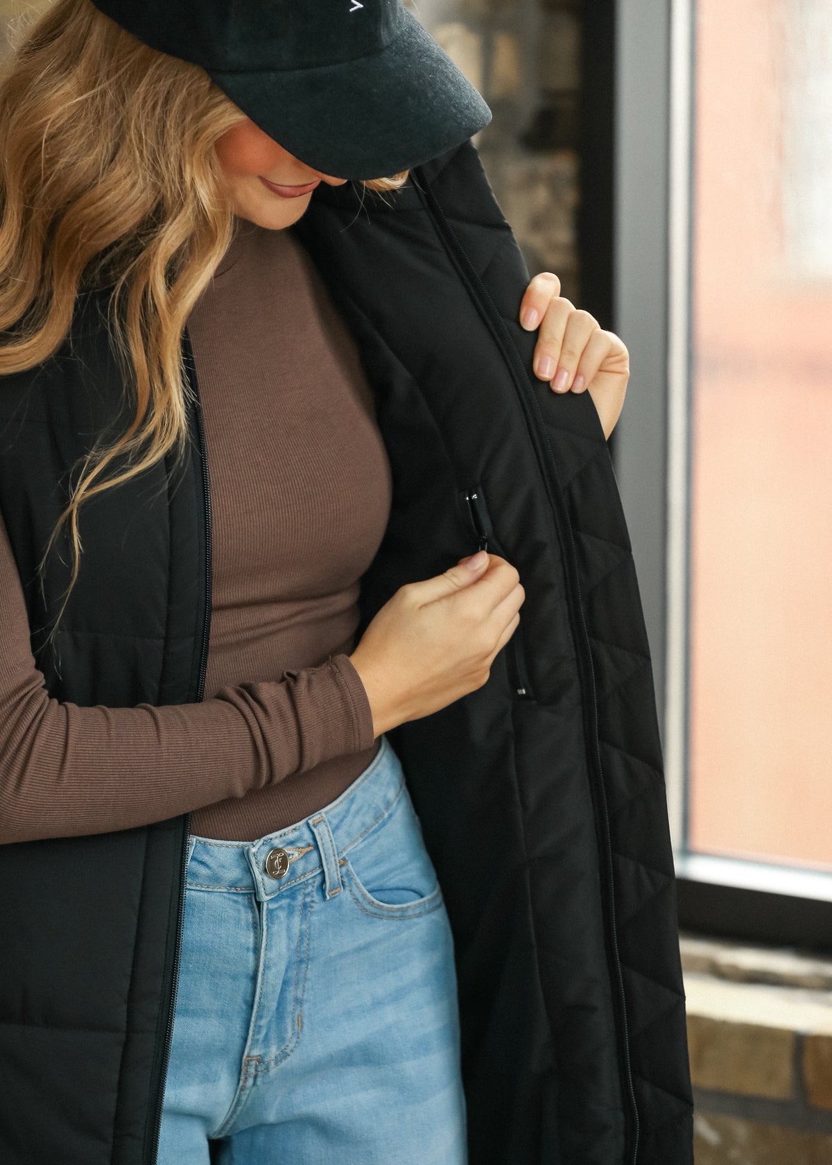 Black long puffer vest shown open, highlighting the loose fit and 35-36 inch length.