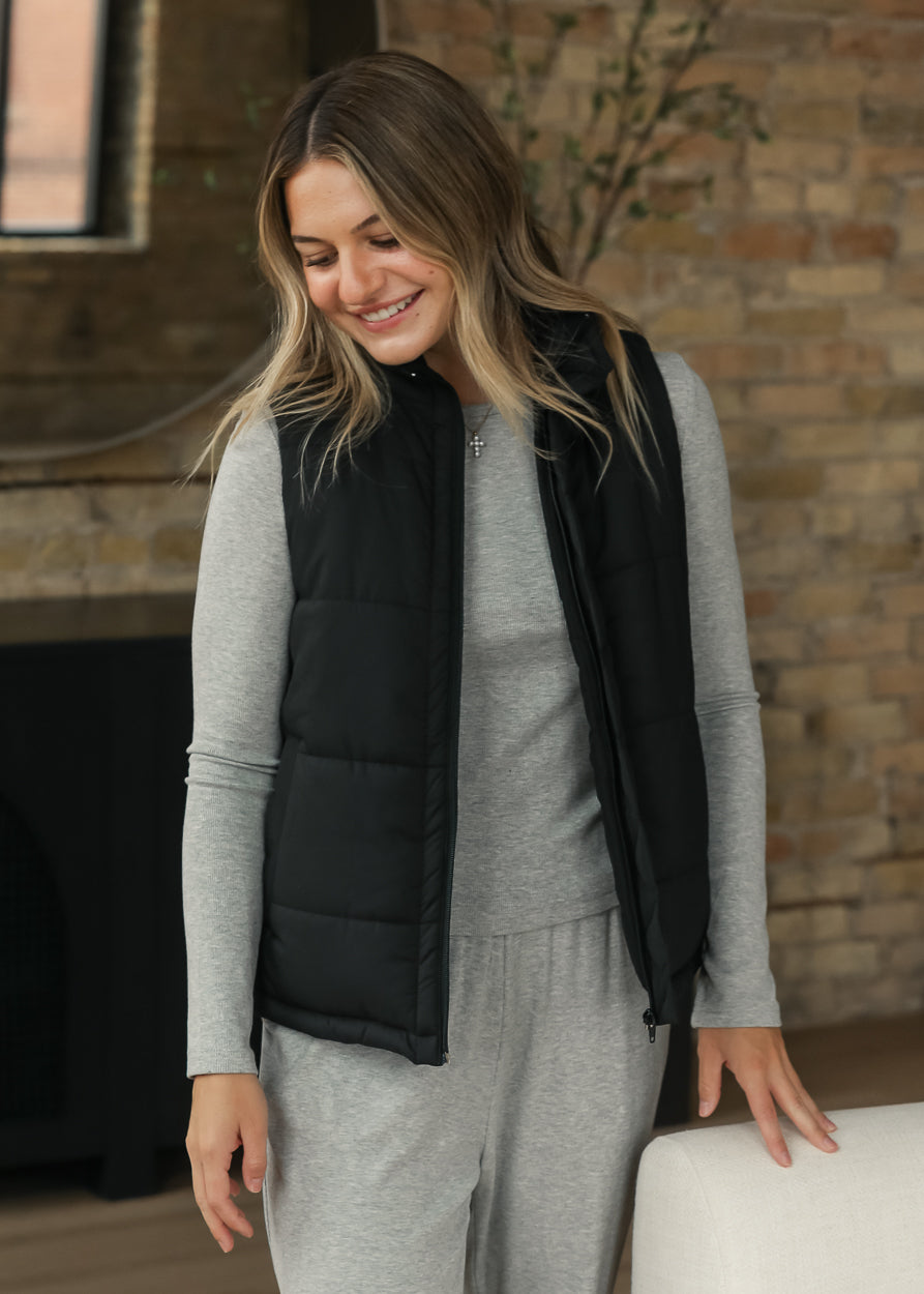 Black short puff vest styled over an espresso long-sleeve outfit for an easy layered look.
