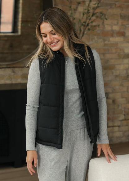 Black short puff vest styled over an espresso long-sleeve outfit for an easy layered look.