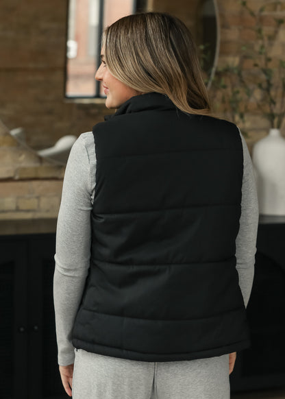 Back of black short puff vest showing the simple sleeveless silhouette.