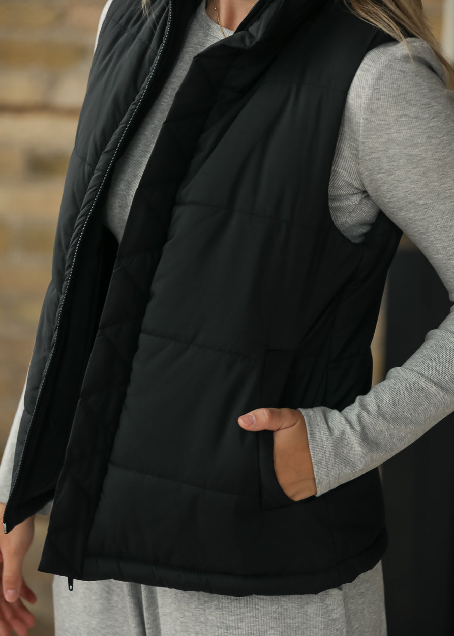 Close-up of black Polar puff vest showing the side pocket and quilted fabric.