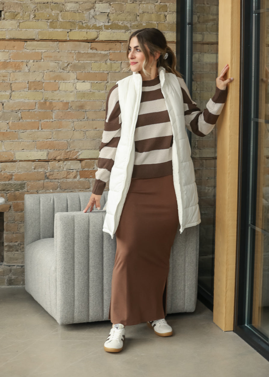 Full-length cream long vest styled for a casual layered look with brown separates.