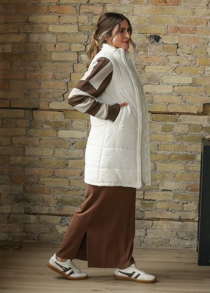 Side view of cream long vest showing quilted texture, patch pockets, and side slit.