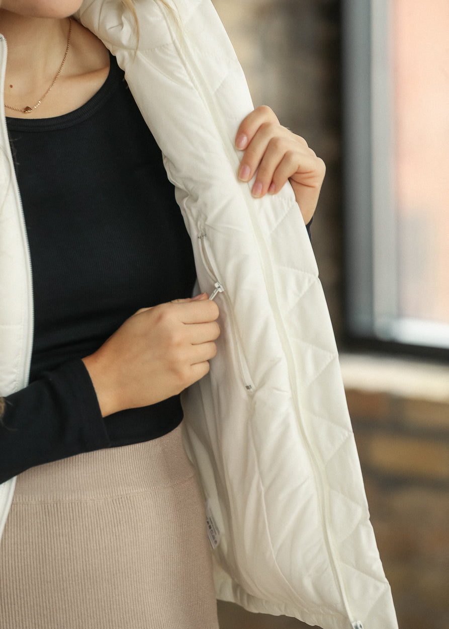 Close-up of cream puff vest showing the side pocket and quilted fabric.