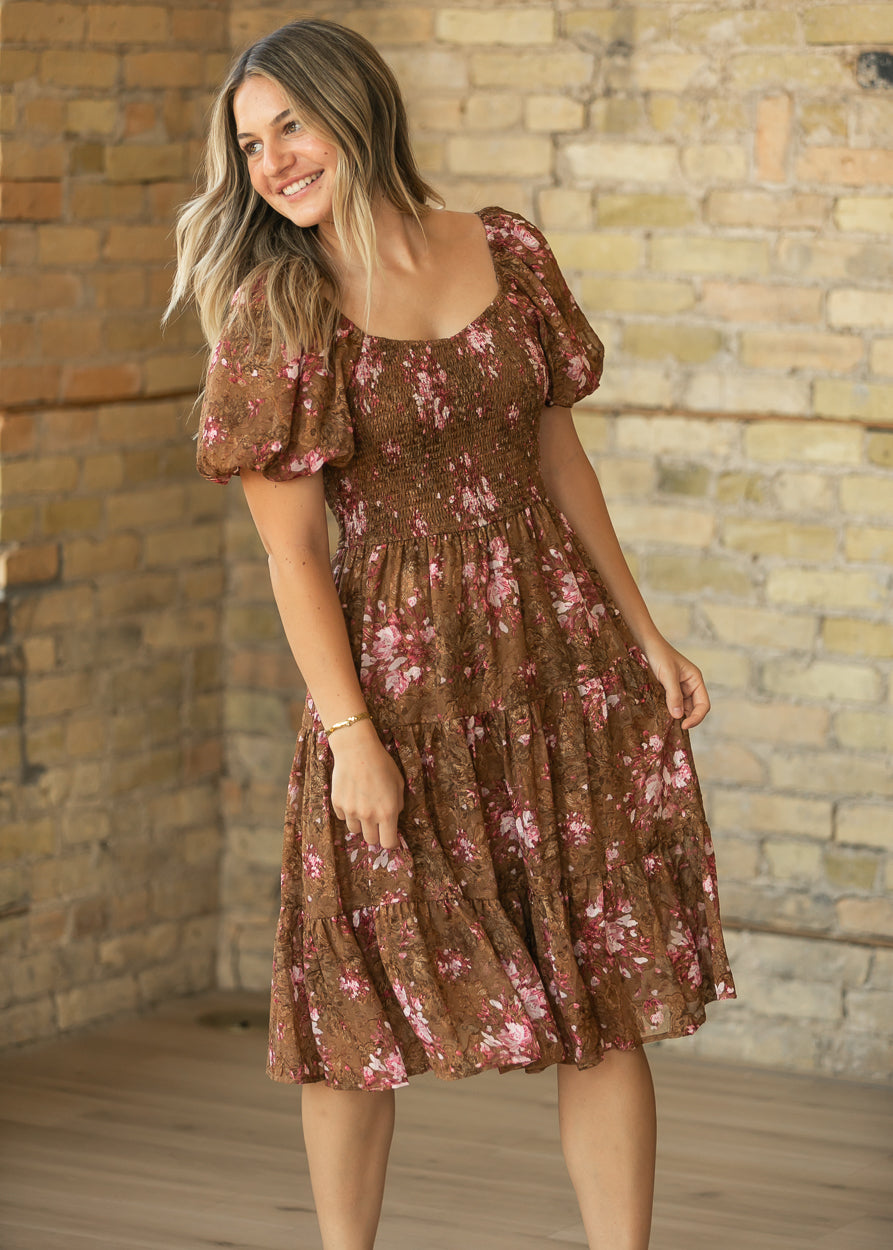 Brown floral midi dress with stretchy smocked bodice, puff sleeves, and softly tiered chiffon skirt.