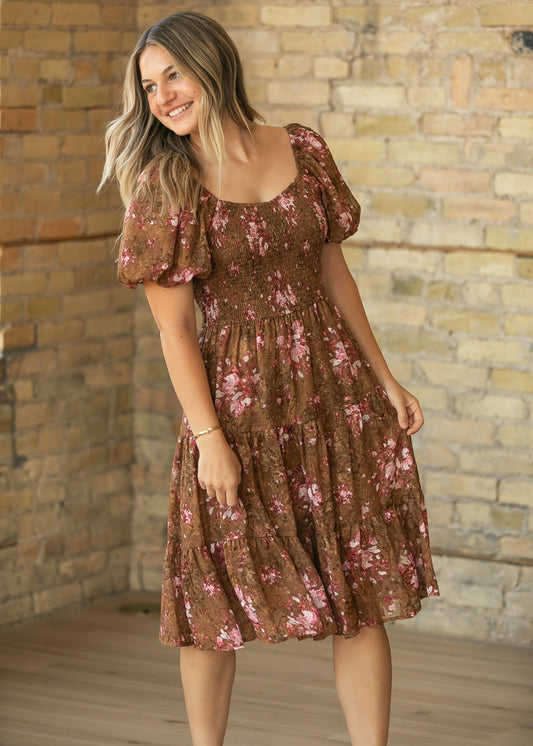 Brown floral midi dress with stretchy smocked bodice, puff sleeves, and softly tiered chiffon skirt.