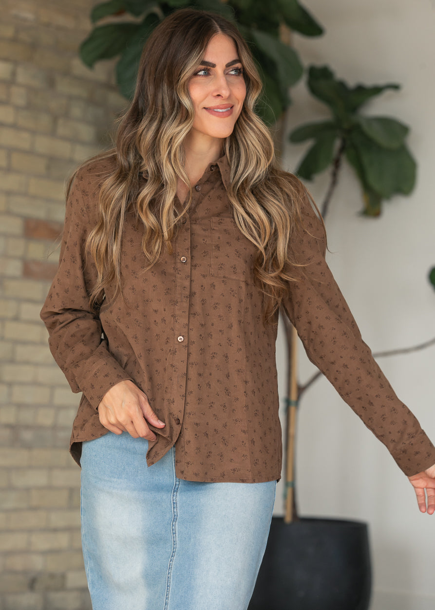 Brown floral print corduroy button-up top with long sleeves, collared neckline, and chest pocket, styled with a denim maxi skirt.