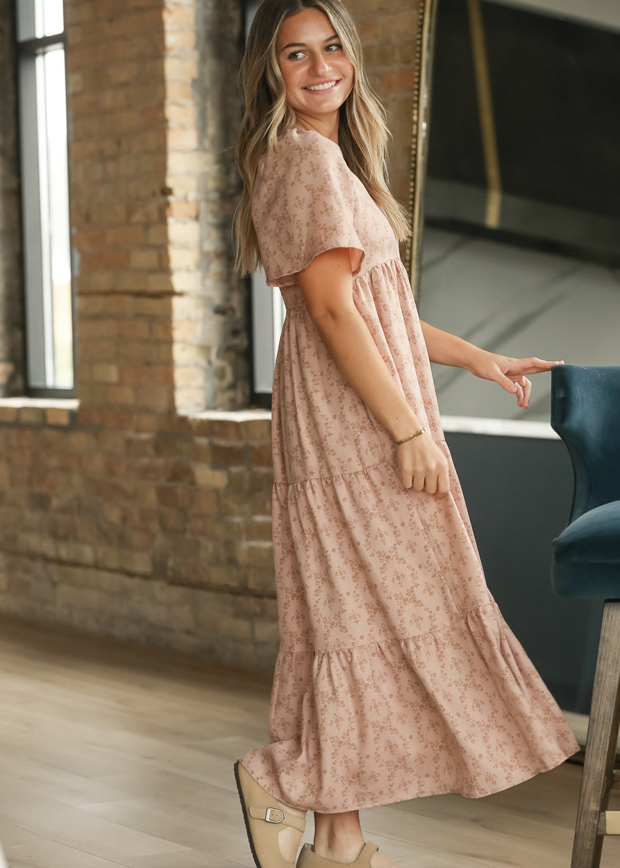Side view of dusty pink floral maxi dress showing flutter sleeves and loose tiered silhouette.