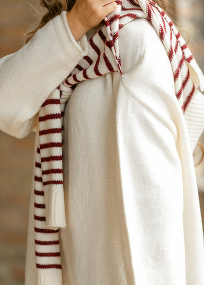 Close-up of soft cream sweater dress knit and red striped shawl detail.