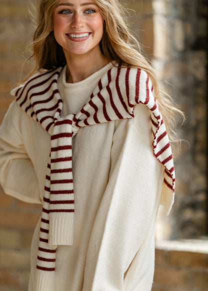 Loose cream sweater dress with long sleeves and coordinating red striped shawl.