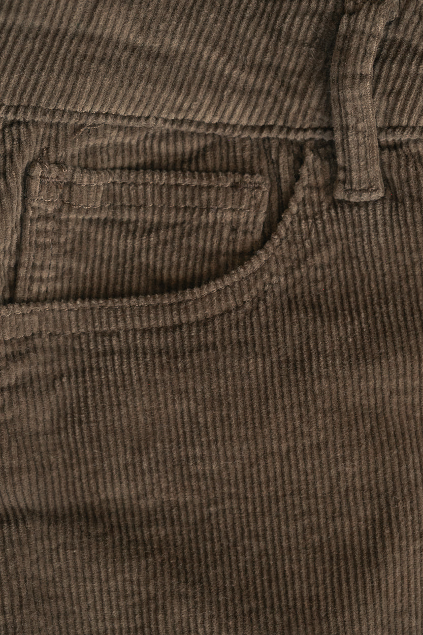 Close-up of brown corduroy pants showing a pocket and ribbed fabric texture.