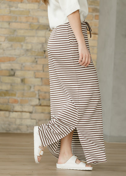 Side view of chocolate stripe maxi skirt showing the pocket, long side slit, and full-length hem.