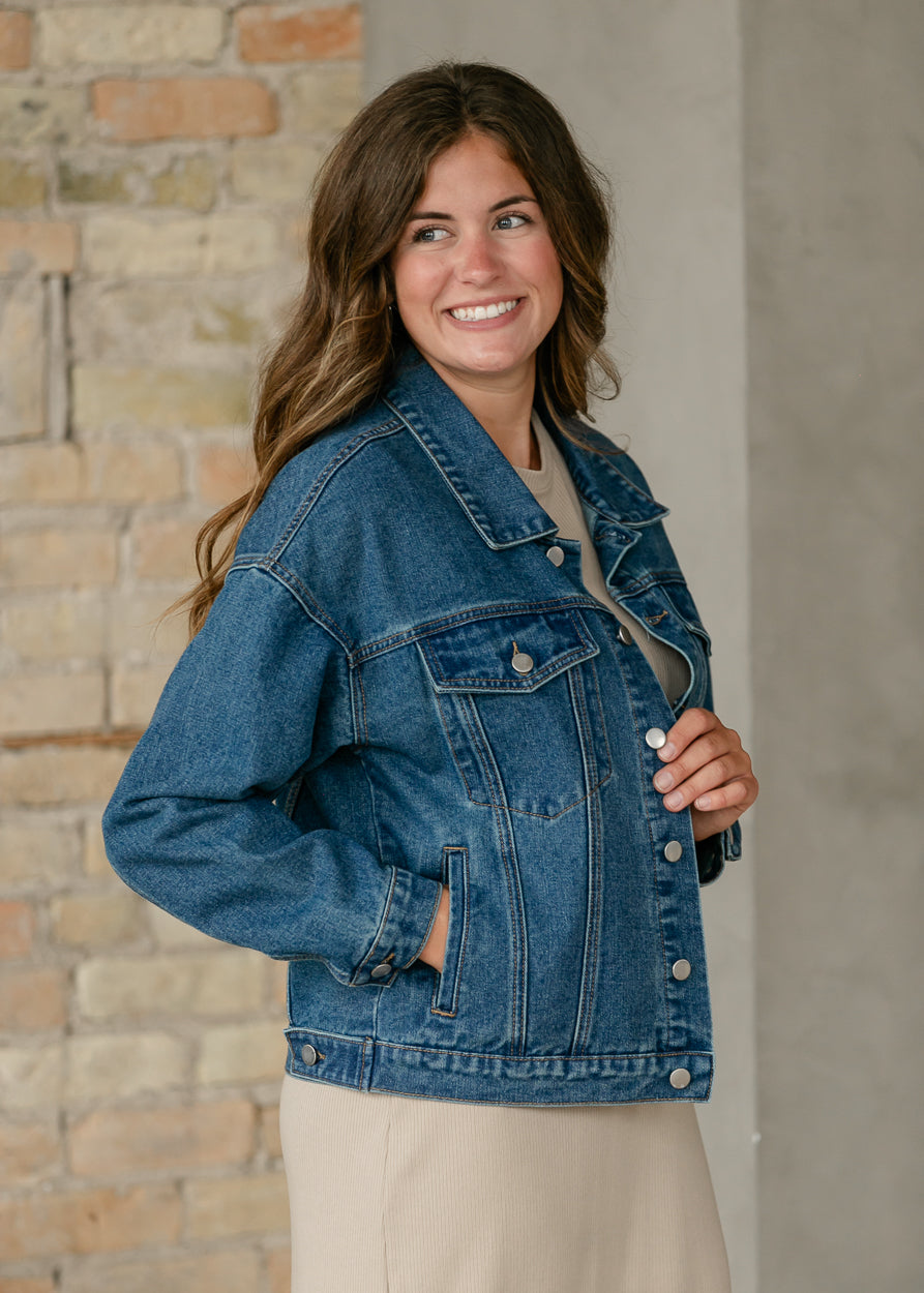 Side view of medium wash denim jacket showing chest flap pocket, side pocket, and relaxed silhouette.