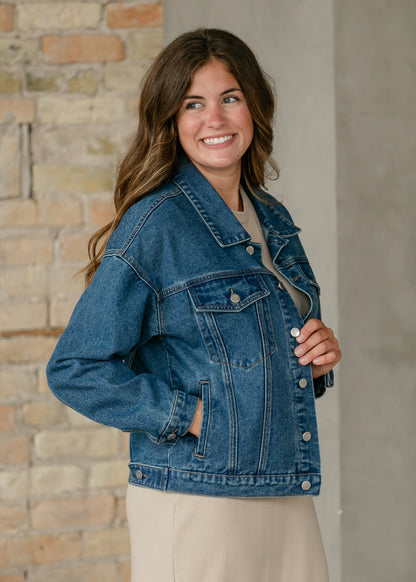 Side view of medium wash denim jacket showing chest flap pocket, side pocket, and relaxed silhouette.