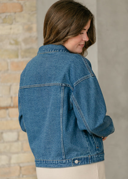 Back of Rue medium wash denim jacket showing dropped shoulders, yoke seam, and structured cotton denim.