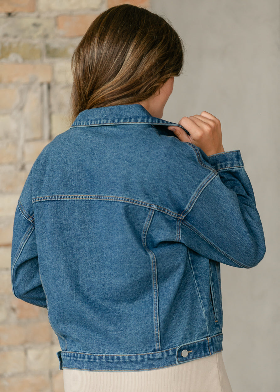 Close-up back view of medium wash denim jacket showing collar, shoulder seams, and classic denim stitching.