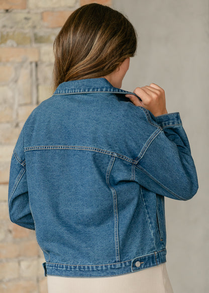 Close-up back view of medium wash denim jacket showing collar, shoulder seams, and classic denim stitching.