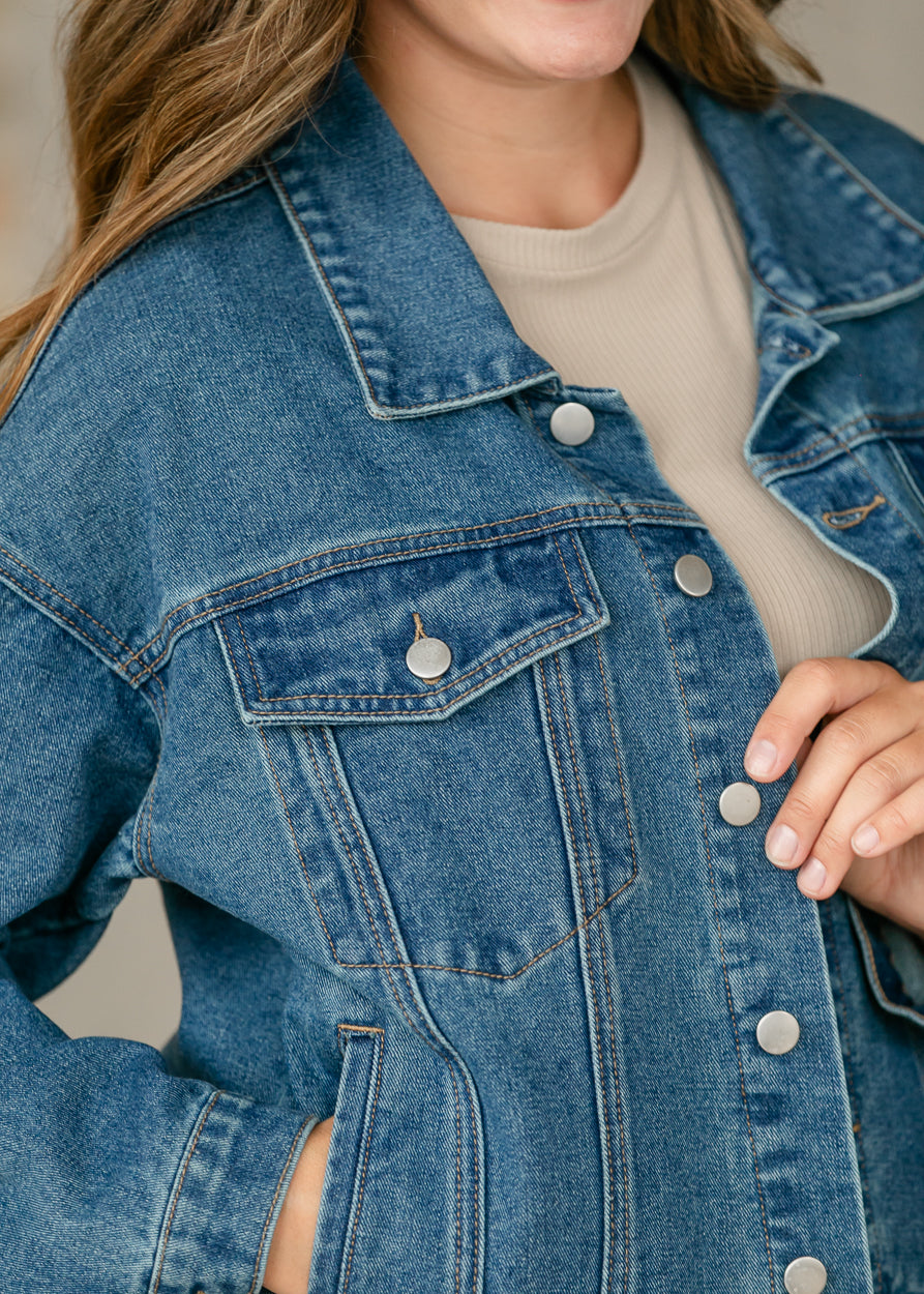 Close-up back view of medium wash denim jacket showing collar, shoulder seams, and classic denim stitching.