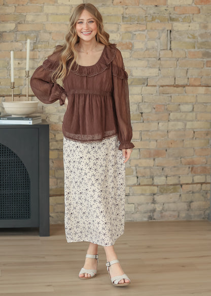 Brown ruffle long sleeve top styled with the Braylyn brown floral midi skirt and neutral sandals.