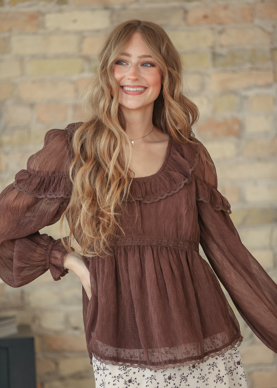 Front view of brown ruffle long sleeve top showing scoop neckline with ruffle and lace trim, empire waist, and lace hem.