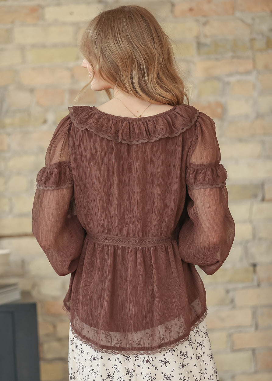 Back view of brown ruffle long sleeve top with ruffled scoop back, lace trim, and sheer lace-edged hem in crinkle fabric.