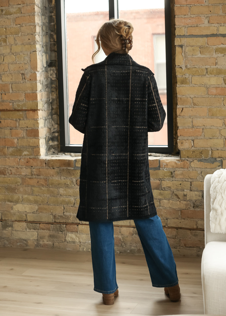 Full back view of black multi houndstooth coat showing the longline shape and warm neutral pattern.