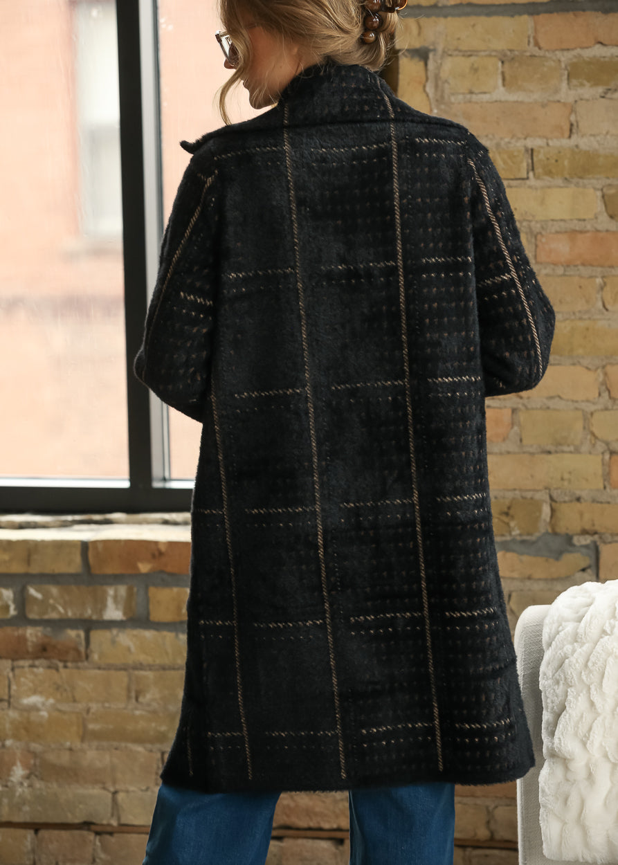 Back view of black multi houndstooth coat showing the oversized knee-length silhouette and long sleeves.