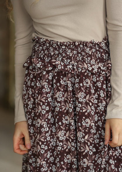 Close-up of brown floral midi skirt showing the wide shirred waistband and ruffle trim.