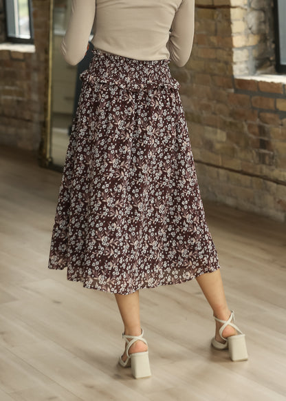 Back view of brown multi floral midi skirt with flowing loose-fit silhouette and shirred waist.