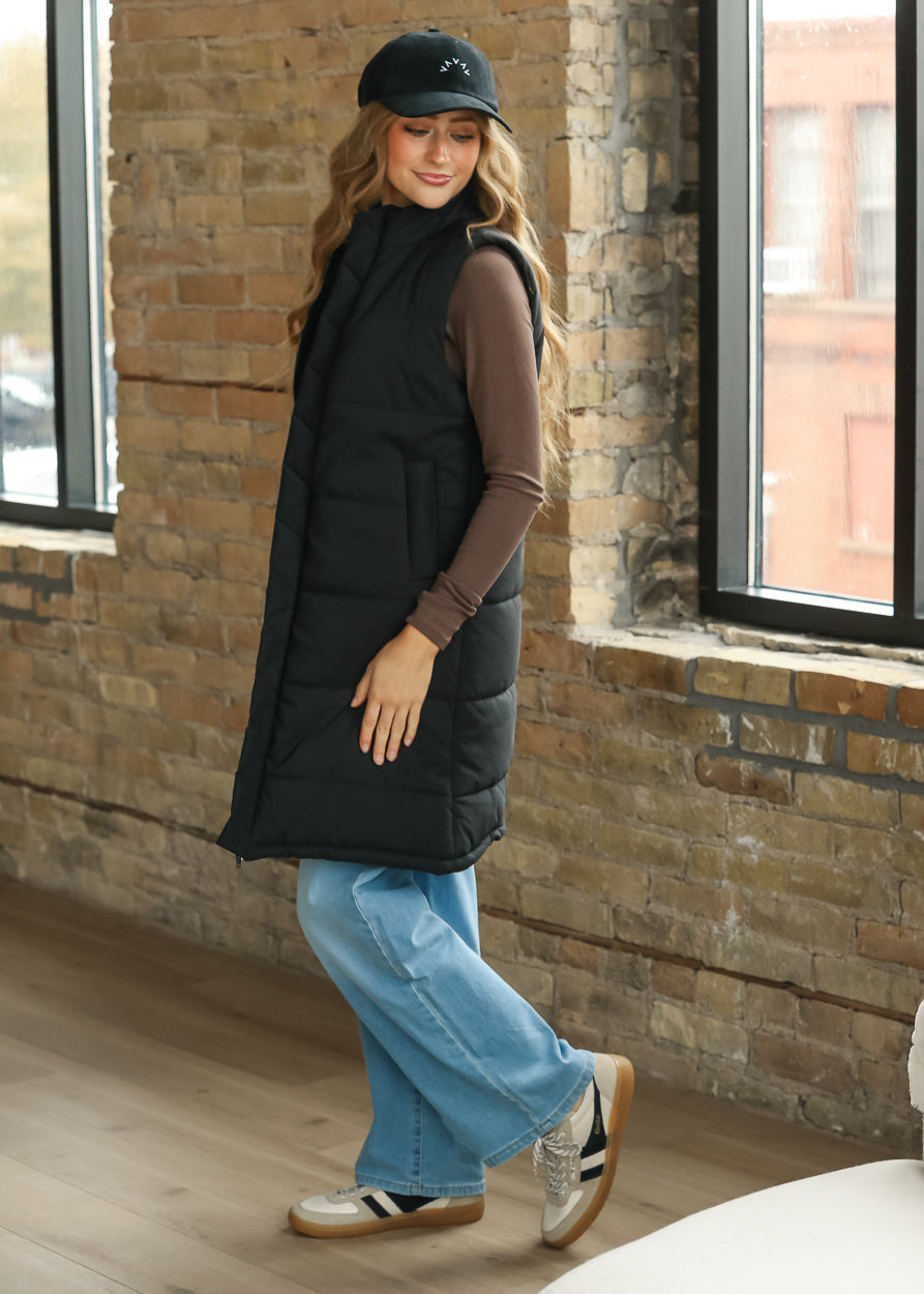 Side view of black Polar vest showing quilted construction and a long layering silhouette.