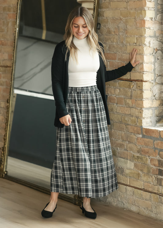 Black plaid A-line midi skirt with gathered waist and full silhouette, styled with a fitted ivory top.
