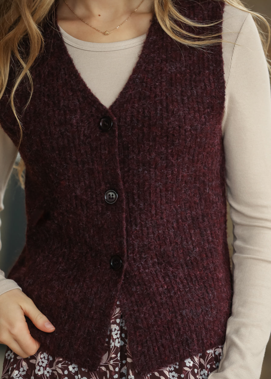 Burgundy sleeveless sweater vest with V-neckline, textured knit, and functional button front.