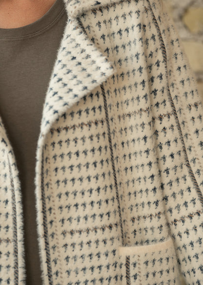 Close-up of cream and blue-gray houndstooth texture, oversized lapel, and contrast seam detail.