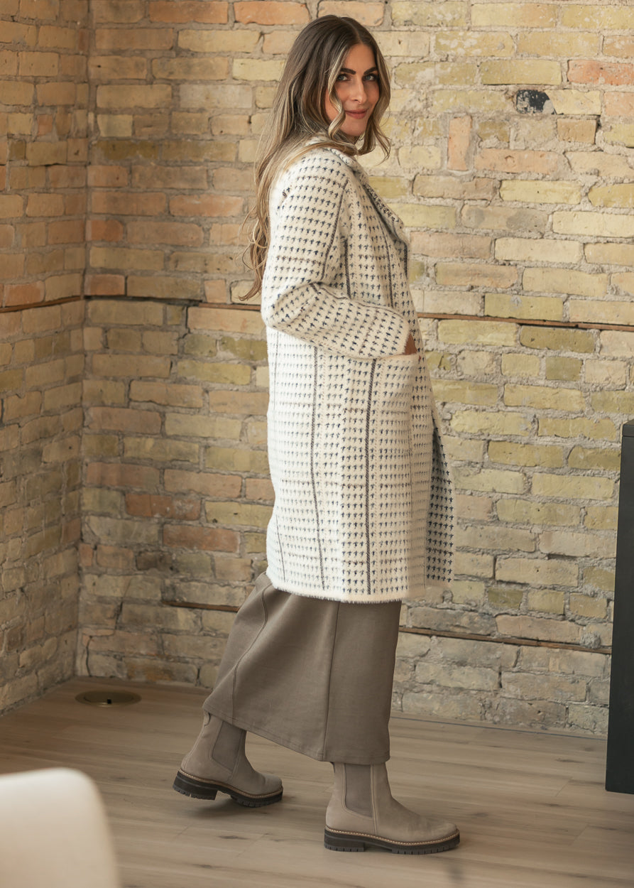 Cream houndstooth coat styled with a taupe maxi dress and tall boots, showing the knee-length side profile.
