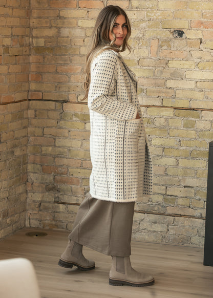 Cream houndstooth coat styled with a taupe maxi dress and tall boots, showing the knee-length side profile.