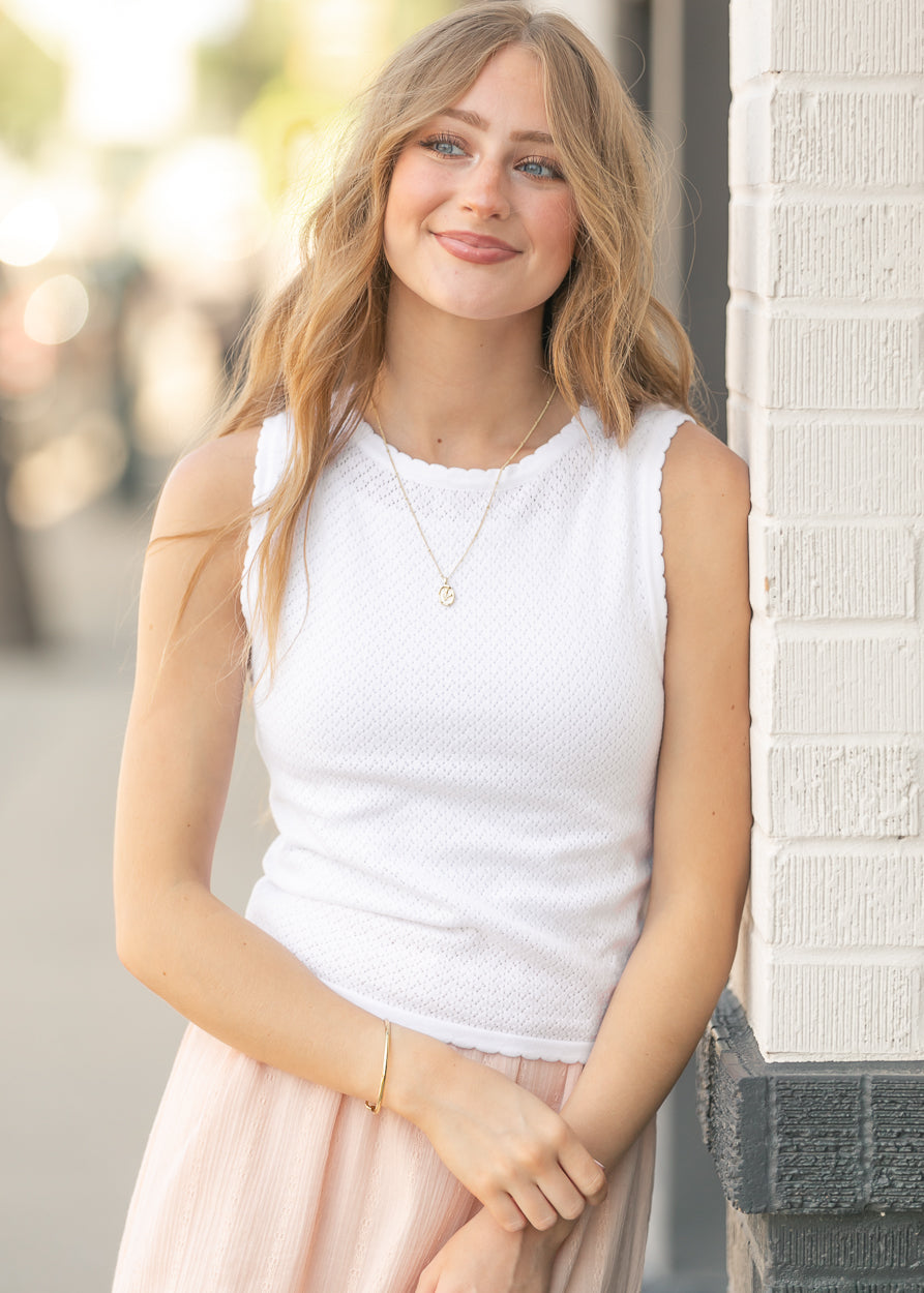 Close-up of white pointelle knit texture with scalloped neckline detail.