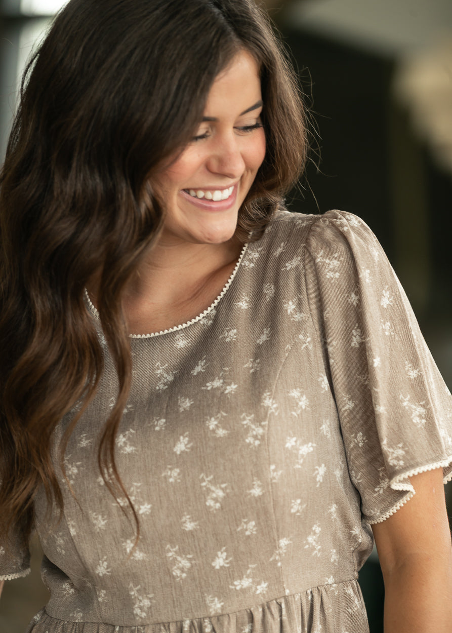 Close-up of brown floral midi dress showing gathered waist, floral print, and functional side pocket.