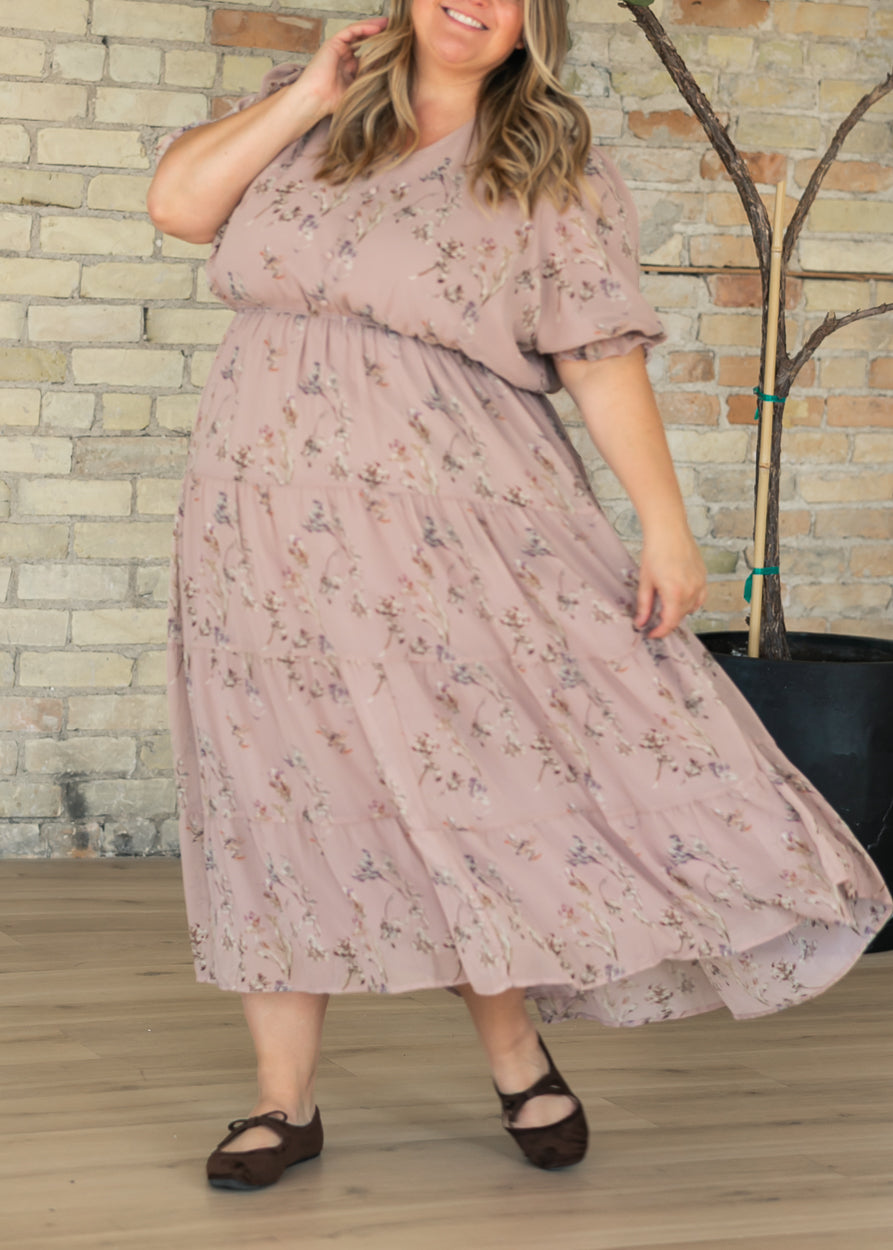 Floral maxi dress with V-neckline, short puff sleeves, elastic waist, and flowing tiered skirt, styled with brown flats.