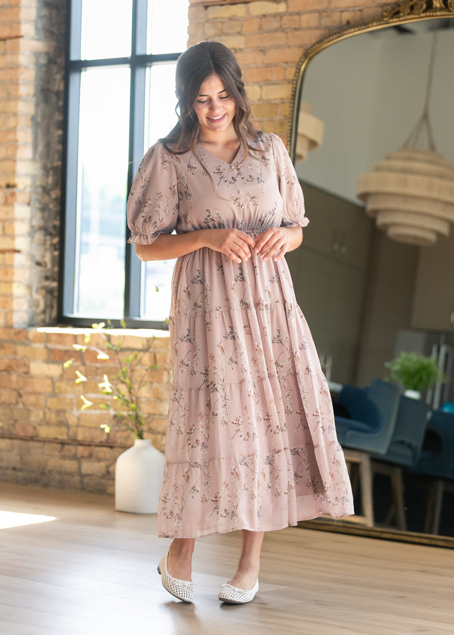 Blush pink floral maxi dress with V-neckline, elasticized waist, short puff sleeves, and tiered skirt.