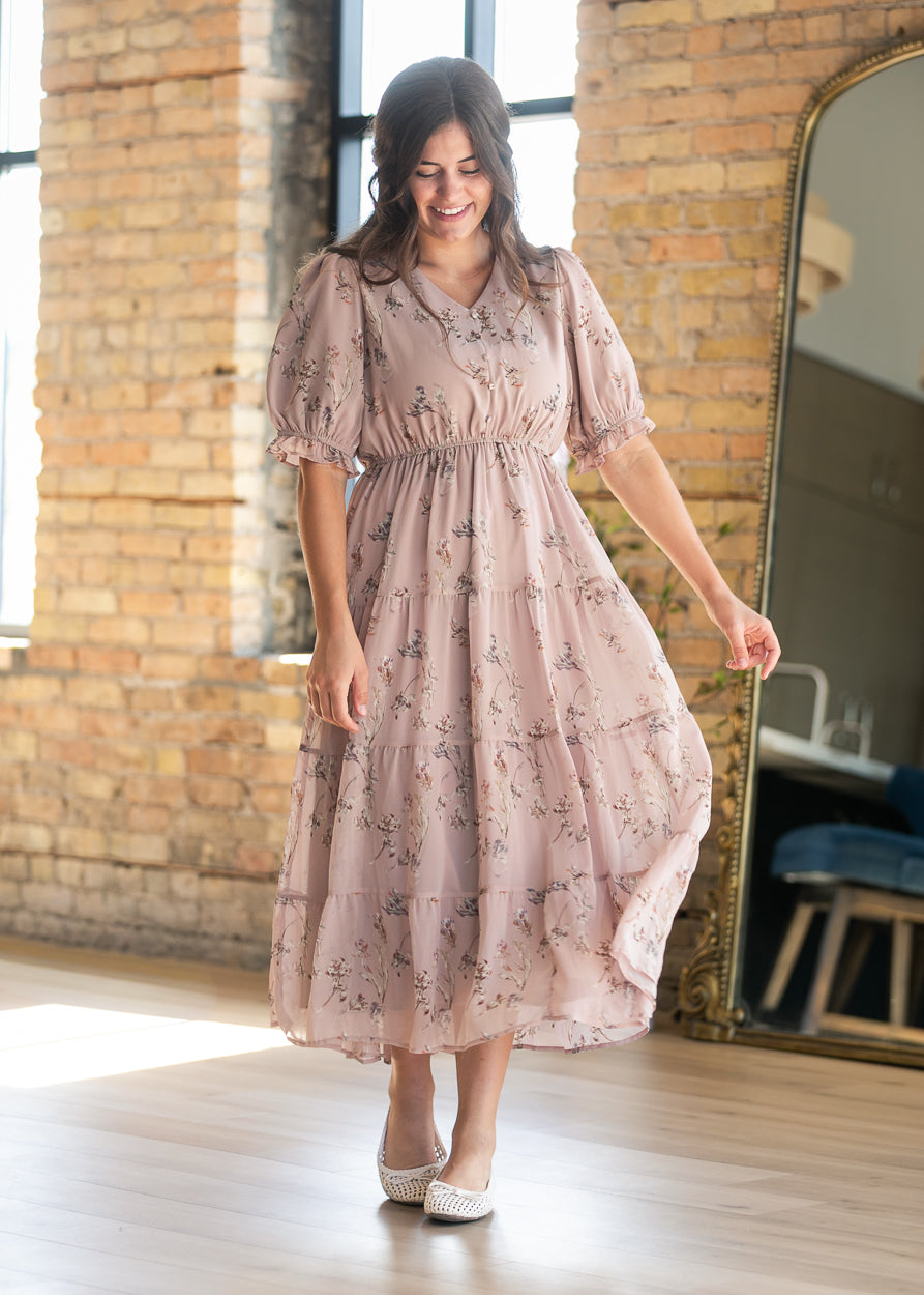 Three-quarter view of blush pink floral maxi dress with V-neckline, short puff sleeves, and tiered skirt.